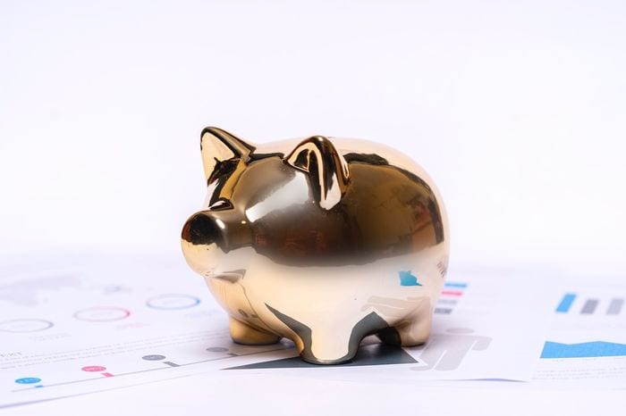 A gold piggy bank sat on paperwork for finacial goals when managing money better.