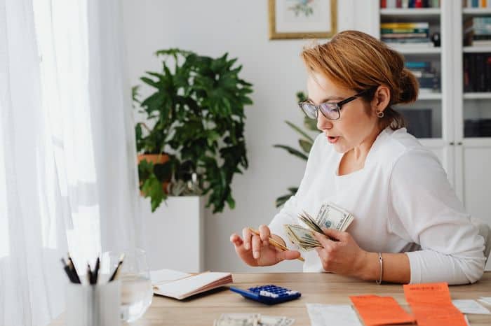 Woman using a calculator whilst sat at a desk when considering better money management.