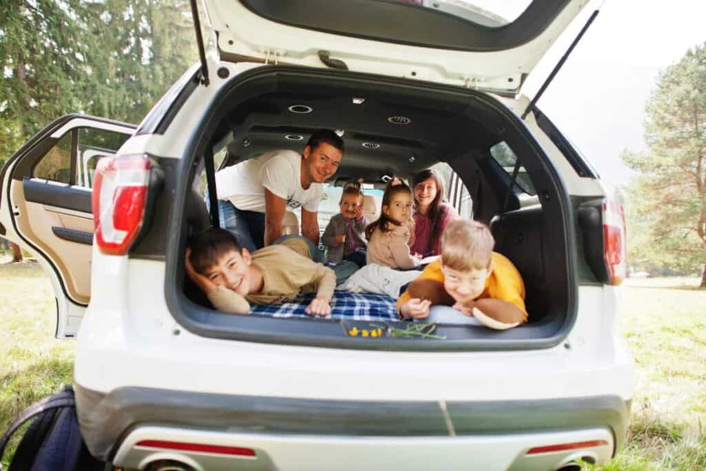 Family relaxing in the boot of a larger car during an outdoor trip