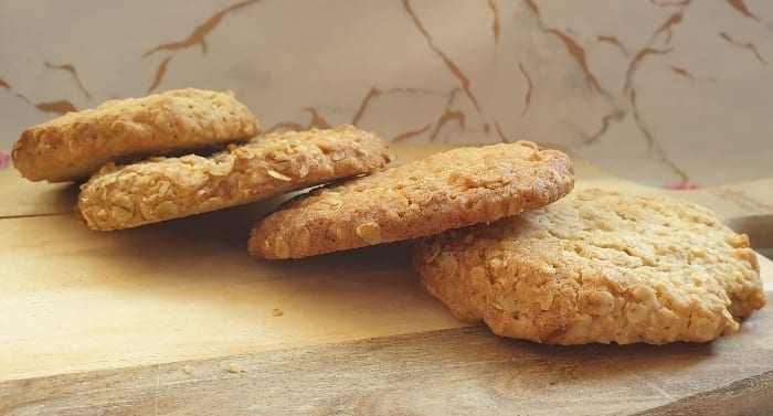 Oat cookies laid out on a wooden bread board.