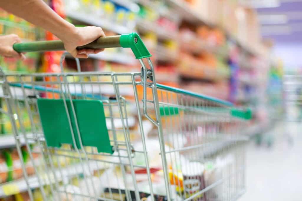 Budgeting tips for parents – pushing a supermarket trolley down the aisle while planning a low-cost weekly shop.