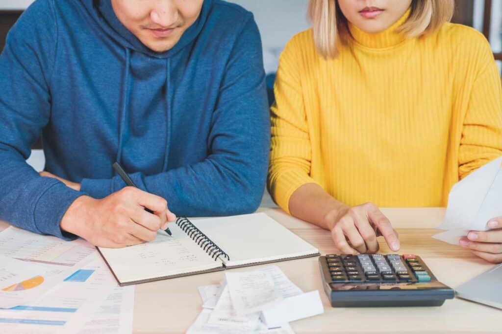 Couple reviewing bills with a calculator and notebook—budgeting tips for parents in action.