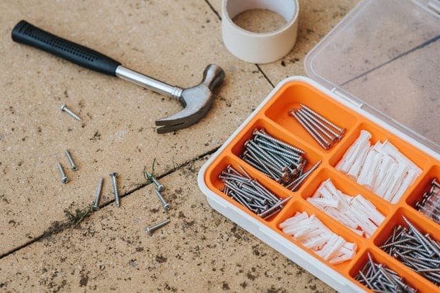 A claw hammer next to a screw set and cup of tea