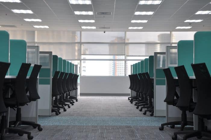 Office furniture with cubicle desks and chairs pushed in.