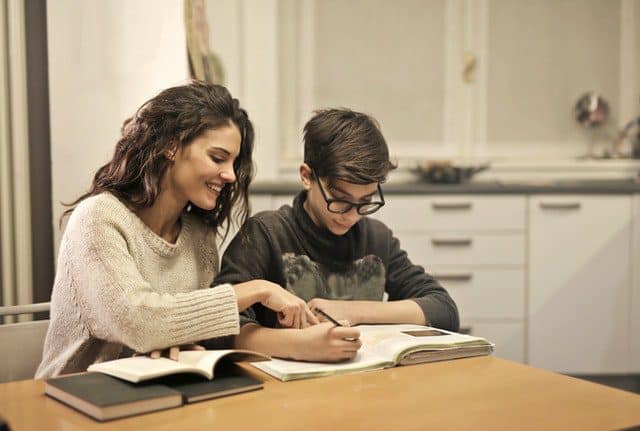 A child and parent sat at a table going through work and critical thinking skills