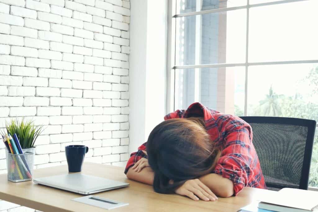 Woman resting her head on a desk showing low motivation and burnout.