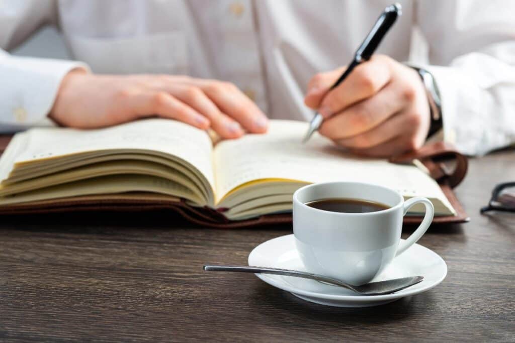 Planning goals in a journal with coffee on a desk