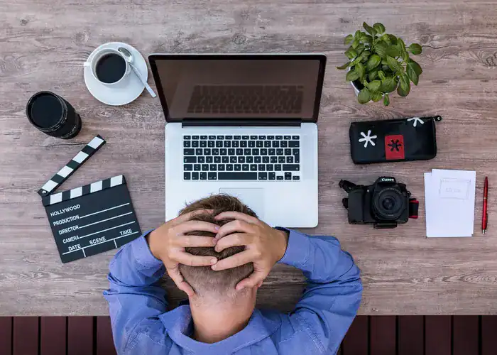 Employer with head in his hands on a desk after employee called in sick.
