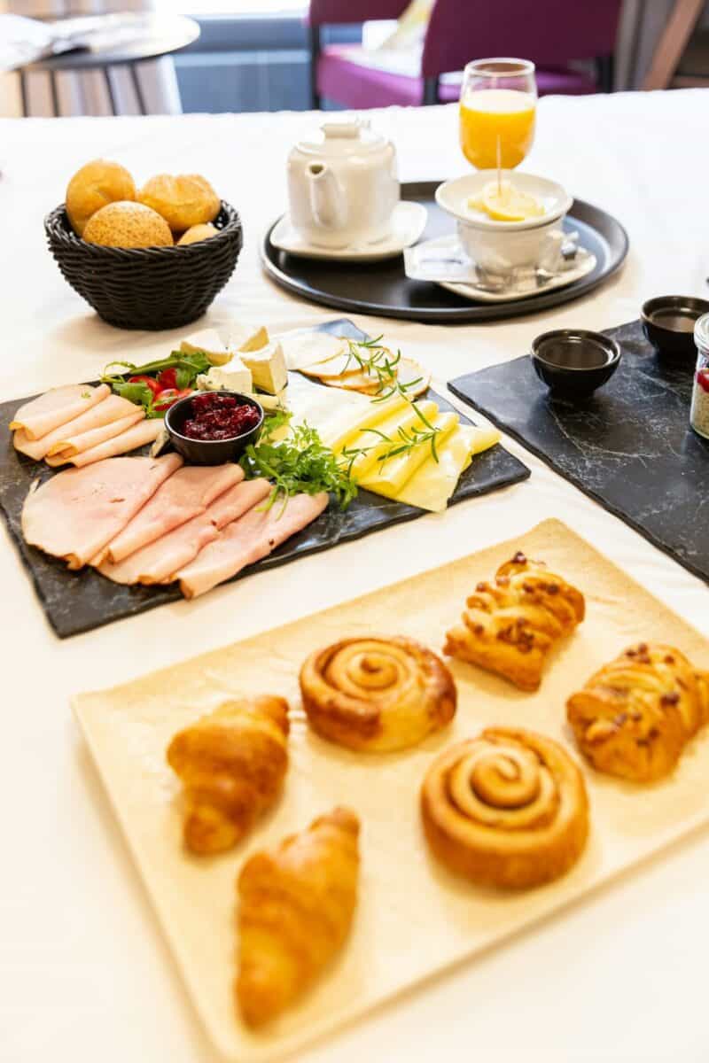 Continental breakfast setup with pastries, cold cuts, cheese, and tea, demonstrating how to run a bed and breakfast.