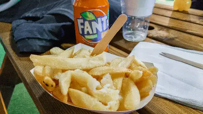 A portion of chips and a can of Fanta on a bench.