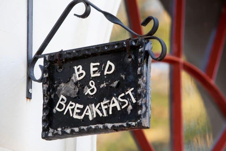 Sign reading 'Bed & Breakfast' hanging on a wrought iron bracket, illustrating a guide on how to run a Bed and Breakfast.