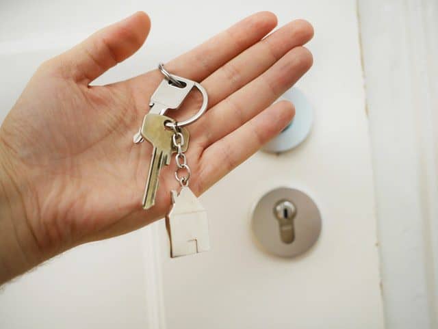 Someone holding keys in front of a door making an investment in property