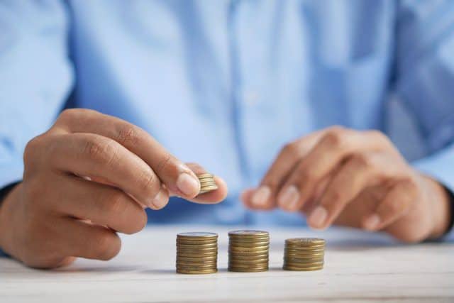 Someone counting a pile of coins from investing in a property