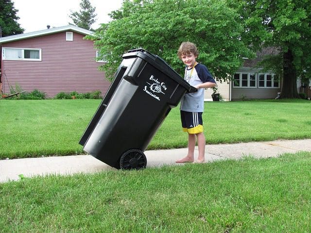 A child understanding the importance of hard work by taking the bin out