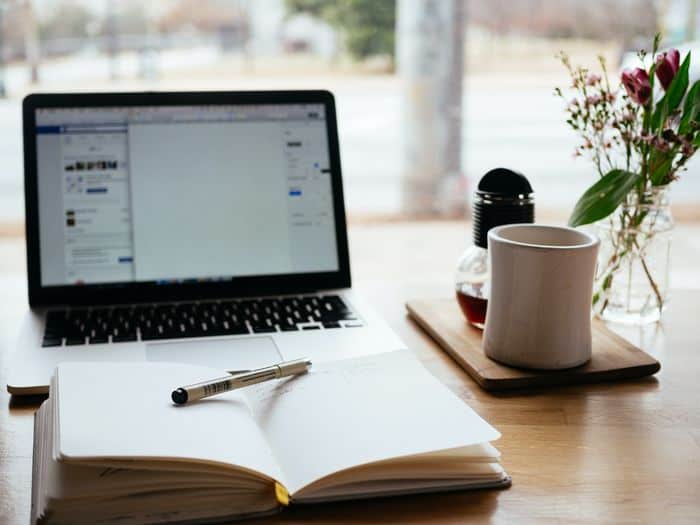 laptop open ready to feature a blog post with an open notebook and pen on a desk