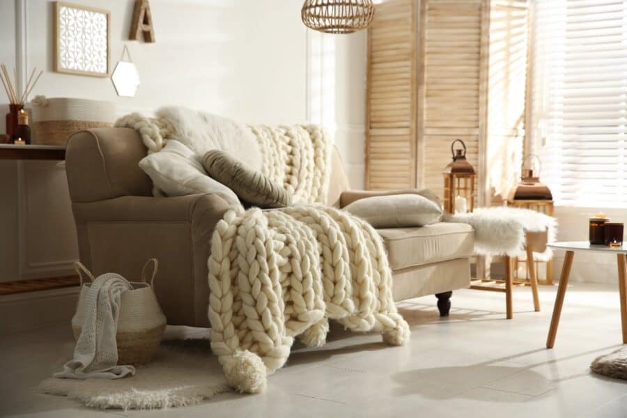 Cosy home refresh with chunky knit blanket, soft cushions, lanterns and warm neutral décor accents.