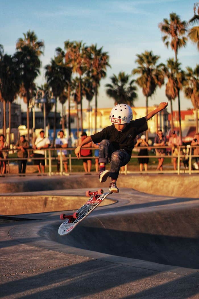 Child skateboarding in a skate park with spectators watching.