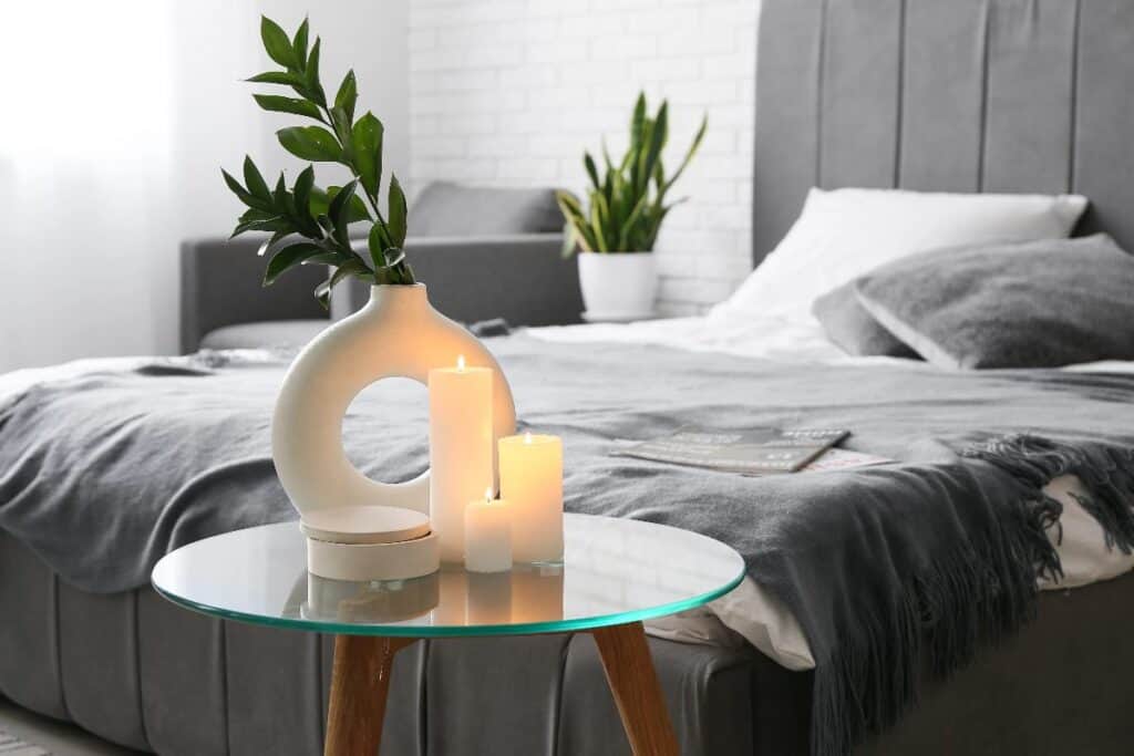 Calm bedroom with candles and plant showing luxury living on a budget