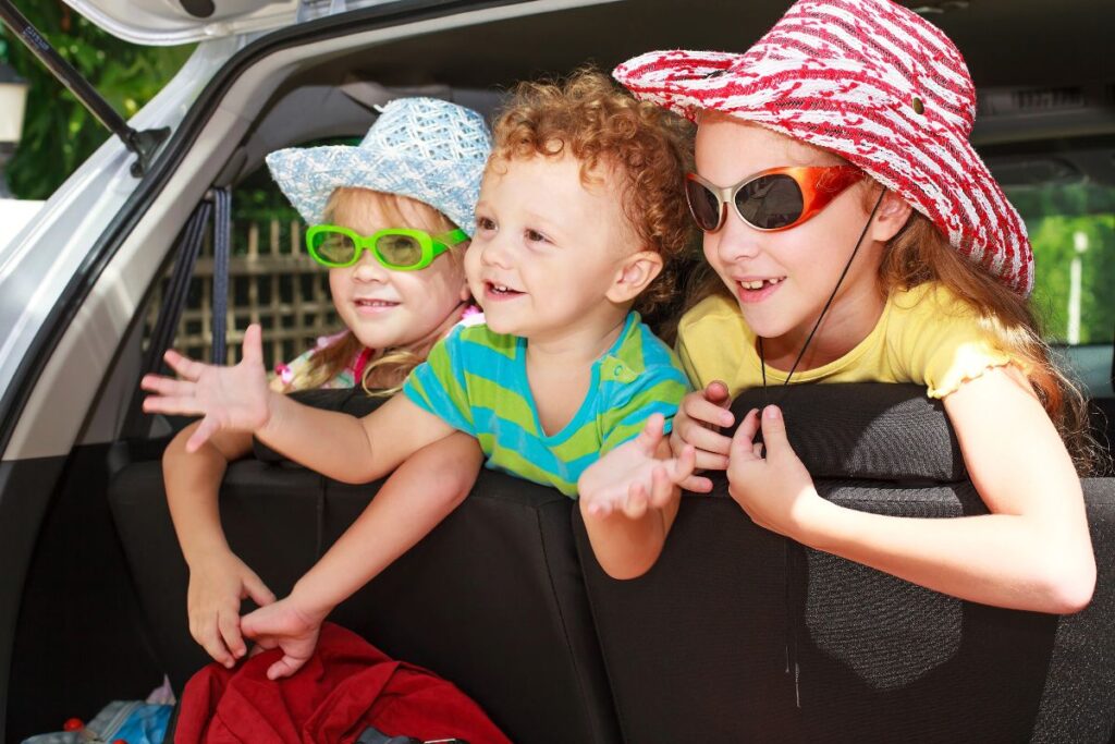 Three children sitting together in the back of a family car