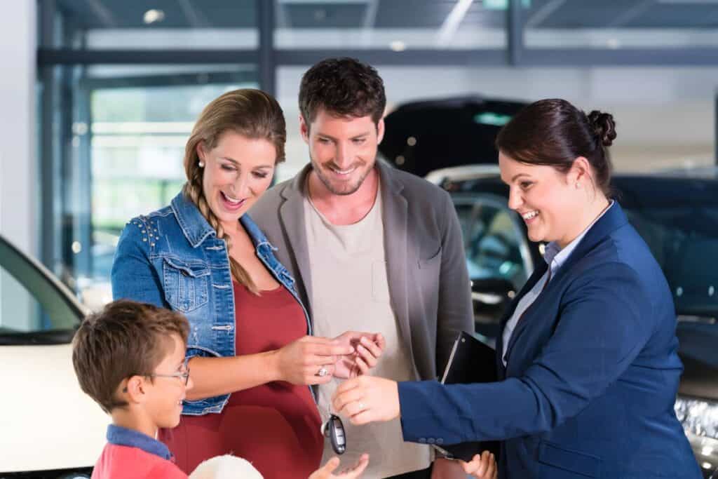 Family receiving car keys from a dealership salesperson