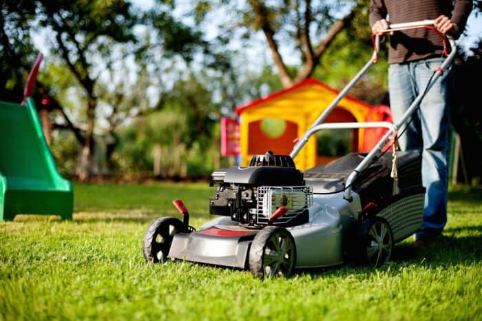 man pushing a lawnmower doing own chore