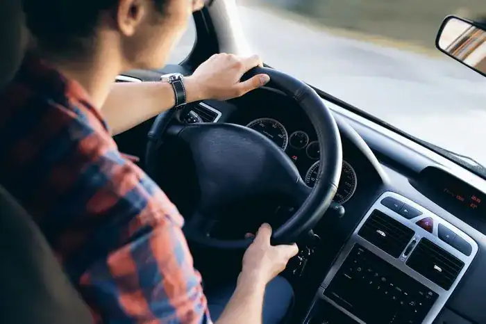 Woman holding a steering wheel and driving a car.