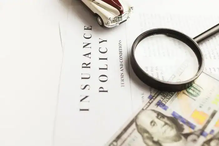 Car insurance policy papers with a magnifying glass lying on top.