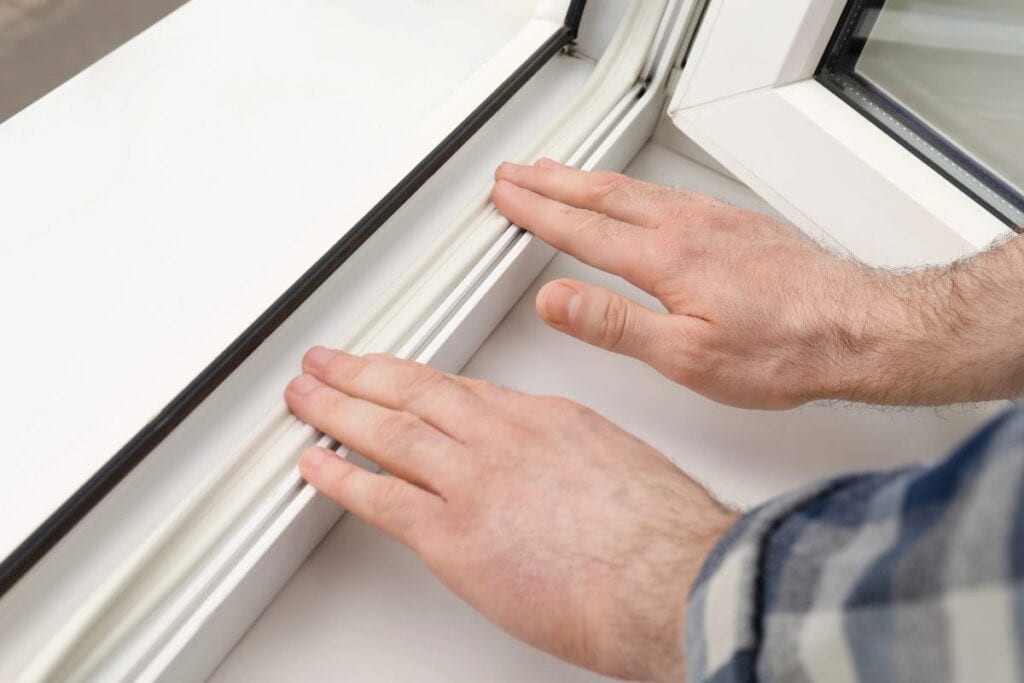 Applying window draught seal on a uPVC frame for extra insulation.