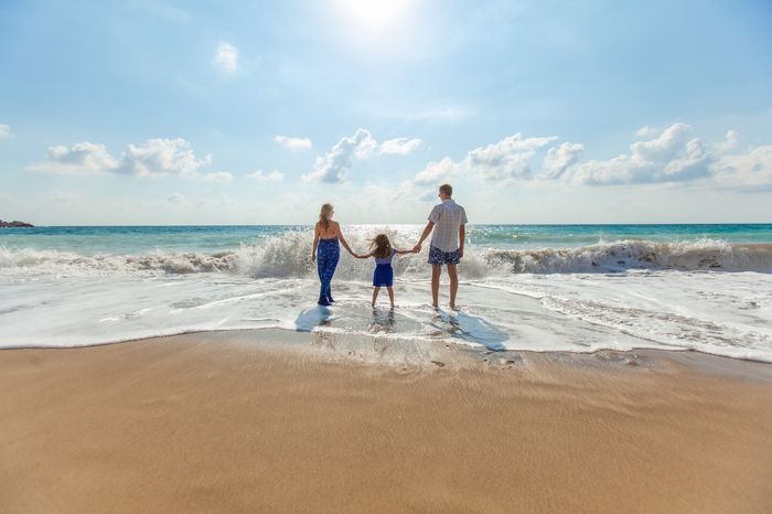 Family holding hands while paddling in the sea.