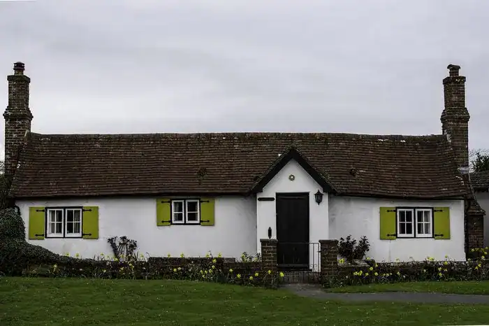A bungalow with white walls and lime green shutters.