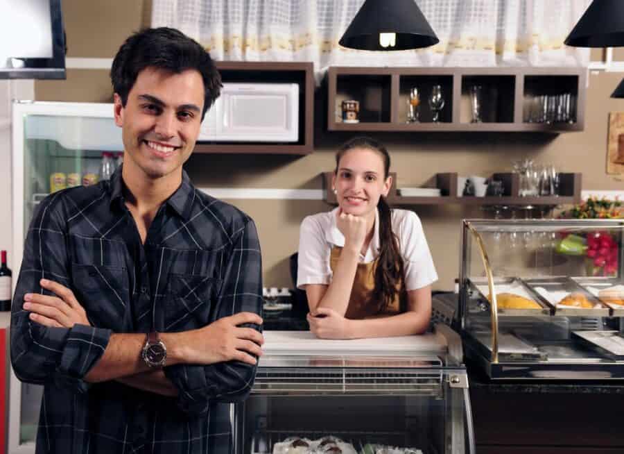 A smiling small business owner and staff member in a café setting.