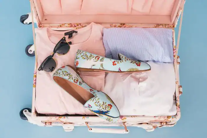 A bright suitcase showng the brightly coloured clothing and shoes packed.
