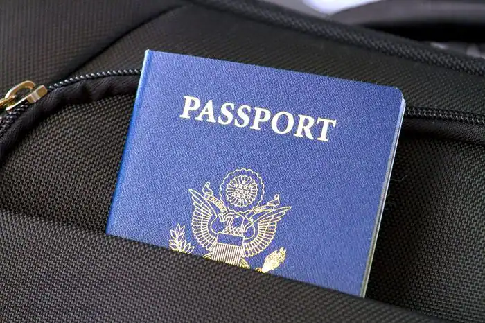 A passport and travel documents packed in the pocket of a black carryon case.