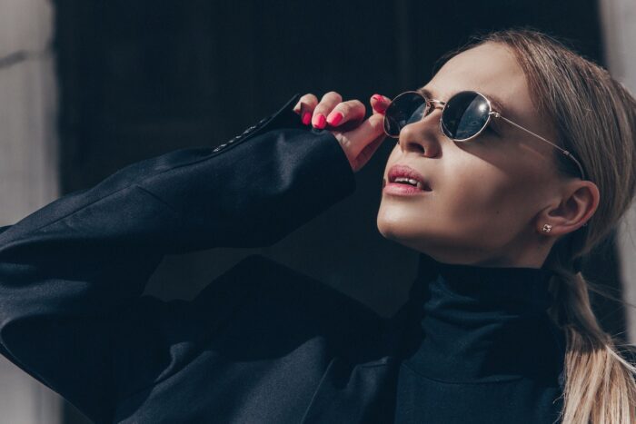 Woman looking up at the sky wearing a pair of oval shaped sunglasses to match her heart shaped face.