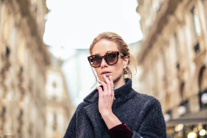 Woman standing in a city street wearing oversized tortoise shell sunglasses for an oval face shape.