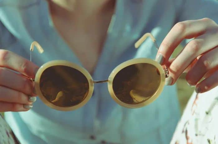 Someone holding round glasses perfect for a round face shape.