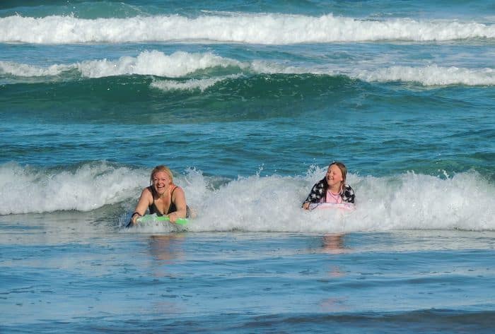 Two women learning to surf in the sea and smiling while making their holiday more memorable.