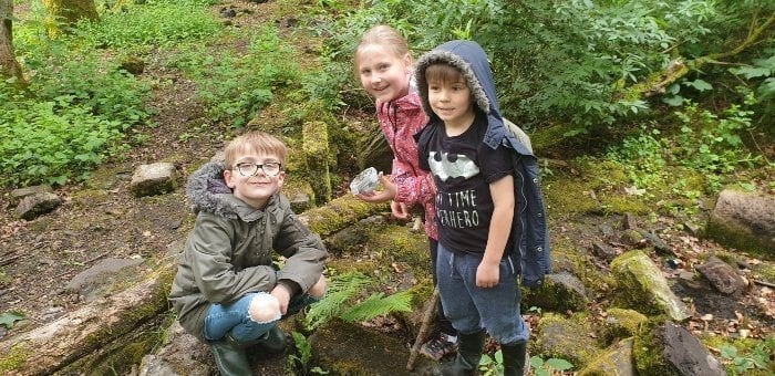 Kids enjoying a fun geocaching activity and holding up the cache they found.