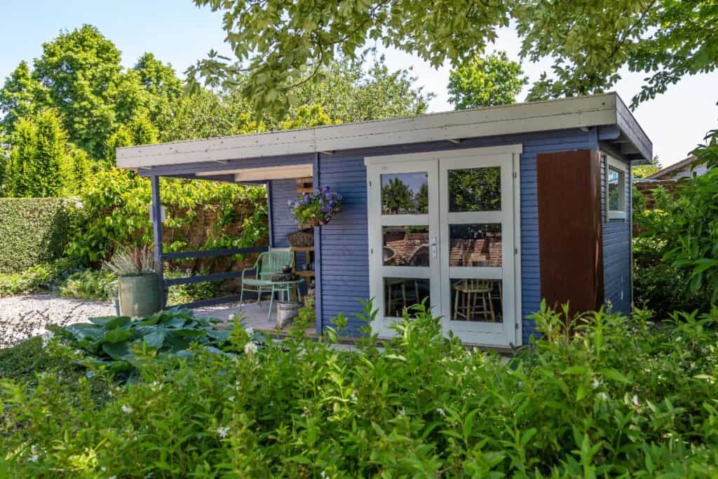 Modern garden shed with patio seating in a landscaped backyard