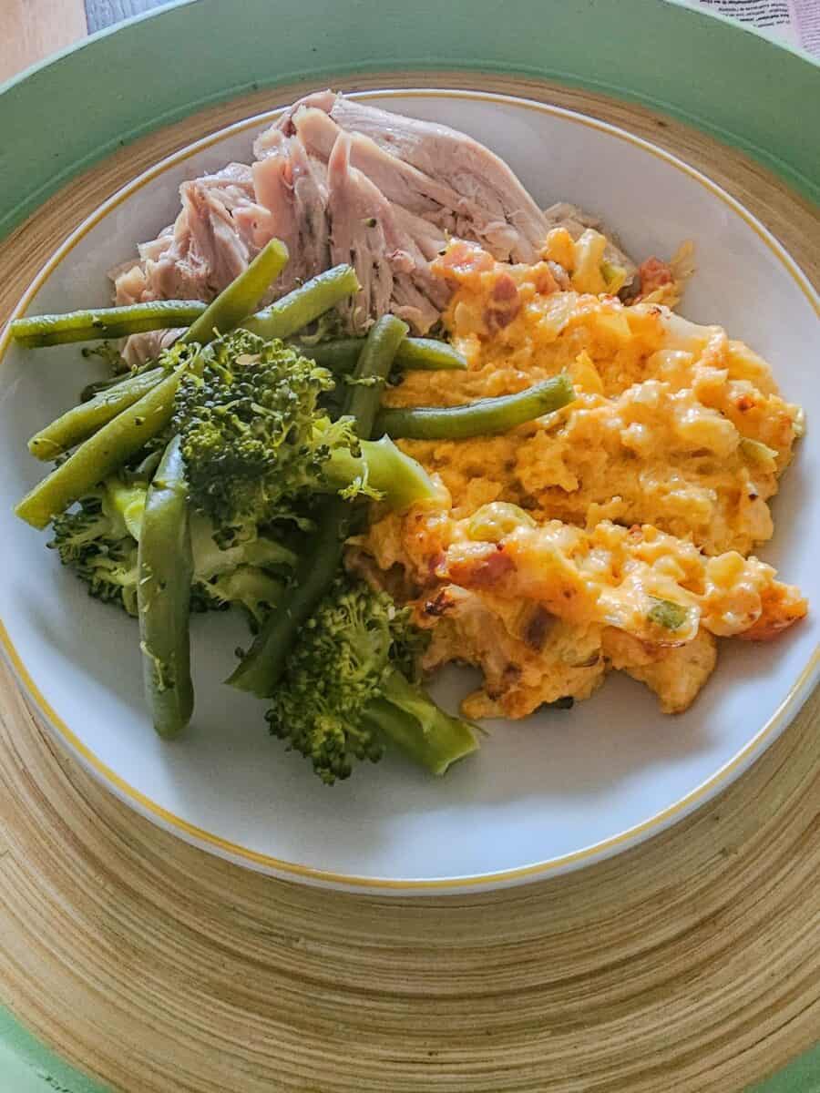 Keto cauliflower cheese in a bowl with roast chicken.
