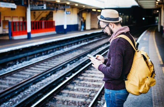 Man waiting at a train station staying connected when travelling abroad.