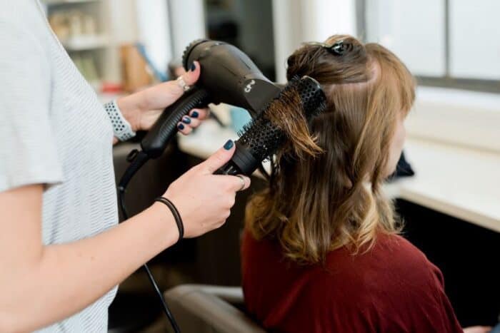 Woman having hair trimmed in a hair salon as part of a good haircare routine.