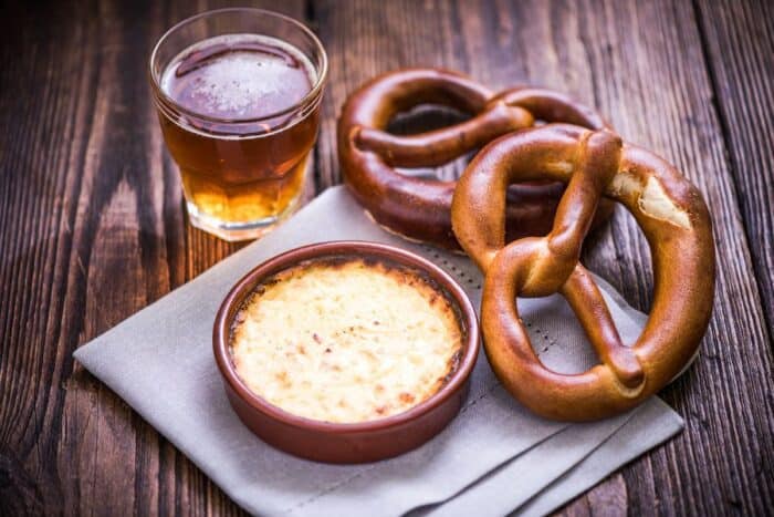 A traditional Swiss fondue meal for Christmas with a pretzel, dish with Gruyere cheese and glass of beer.