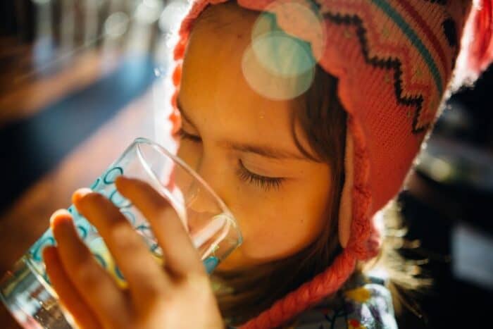Child drinking water from a glass, understanding why hydration is important for children.