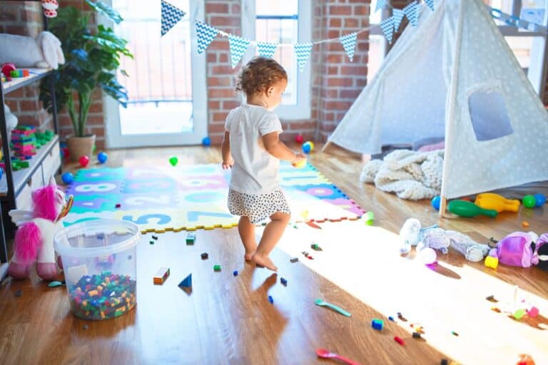 A perfectly designed playroom featuring colorful foam mats, organized toy storage, a cosy play tent and scattered toys, creating a fun and functional space for children.