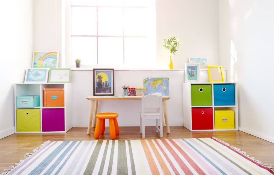 A bright and colourful playroom with a striped rug, storage cubes, and a child-sized desk, designed for creativity and organisation.