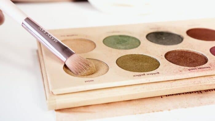 Someone dipping a Mary Key makeup brush into a colourful eyeshadow palette.