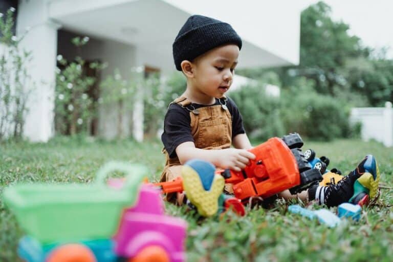 A child playing outsside with toys and feeling the benefits of sensory outdoor play for children.