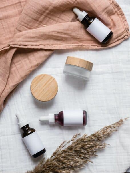 Empty skincare and beauty products on a flatlay with a blush pink throw.
