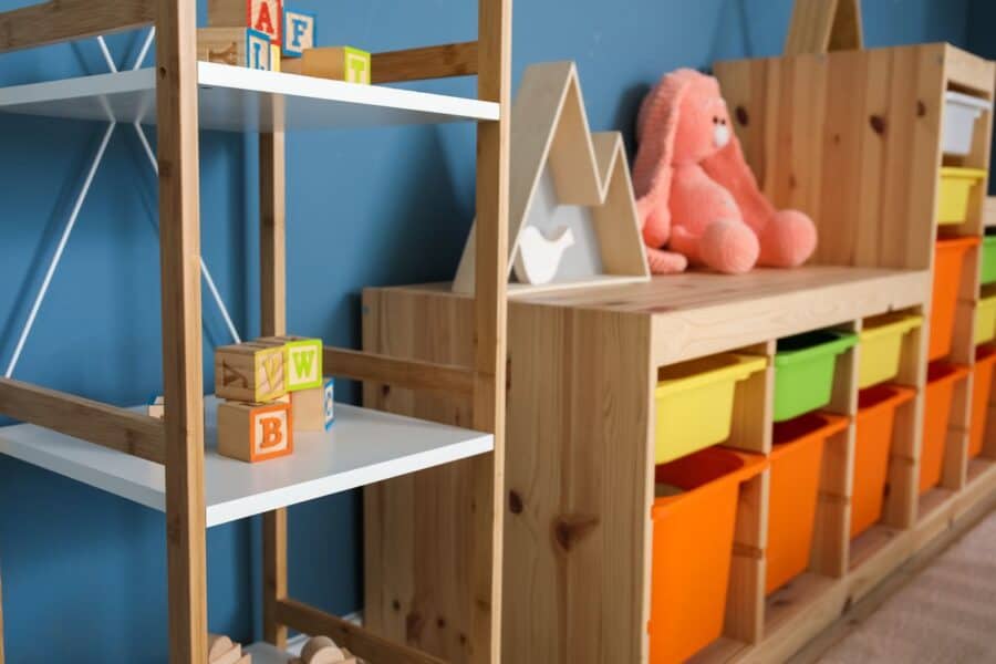 A well-organised playroom storage solution with wooden shelves, colourful bins, and playful accents,